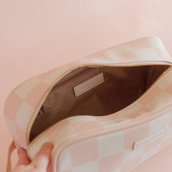 Pink checkered bag with a visible brand label on a pink background