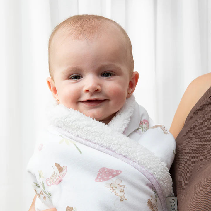 Baby wrapped in a floral blanket with a blurred background