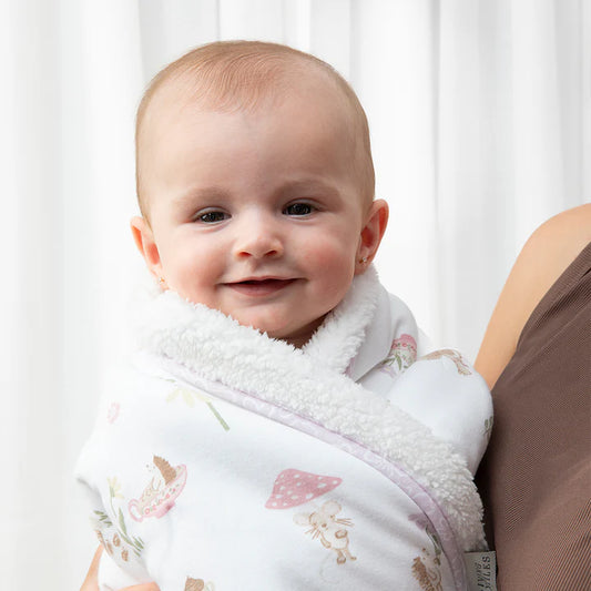 Baby wrapped in a floral blanket with a blurred background