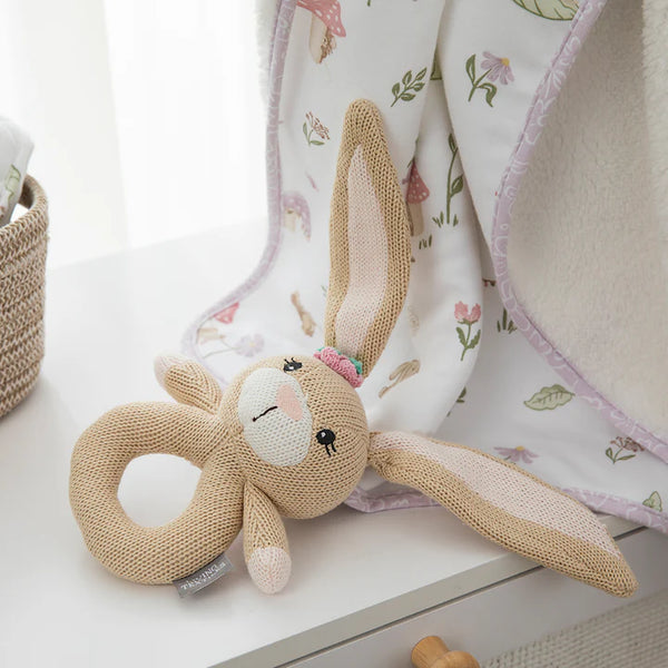 Knitted bunny toy with a rattle on a floral blanket