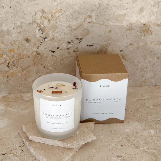 Candle with a box labeled 'Pomegranate' on a textured stone surface
