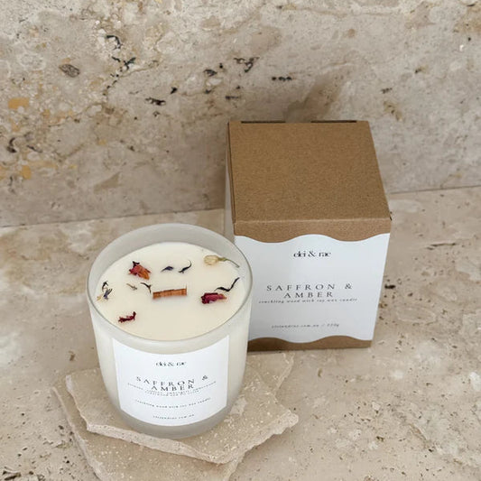 Candle with 'Saffron & Amber' packaging on a stone surface
