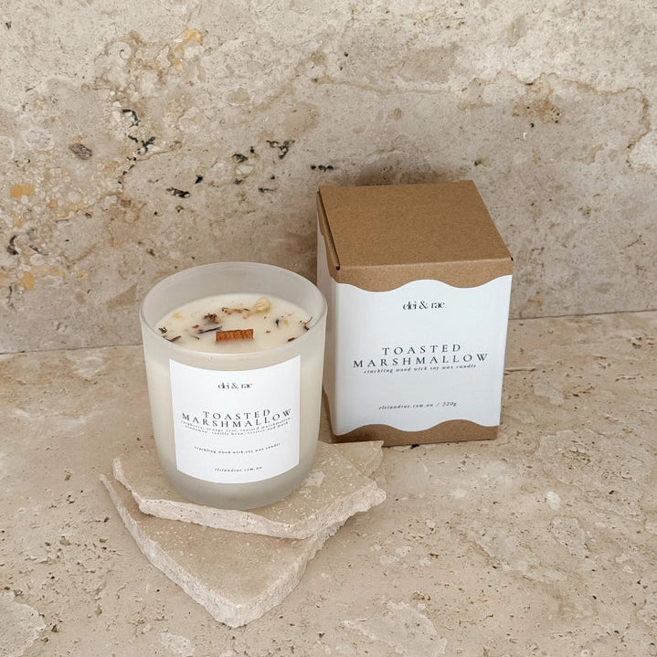 Toasted marshmallow candle and packaging on a stone surface