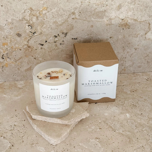 Toasted marshmallow candle and packaging on a stone surface