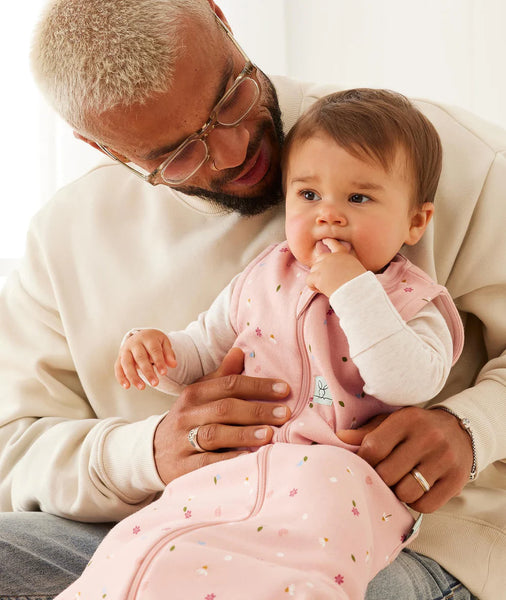 Man holding a baby in a pink outfit against a white background