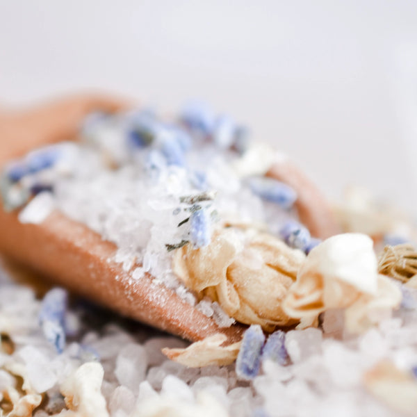 Close-up of a wooden spoon filled with white and blue dried flowers on a light background