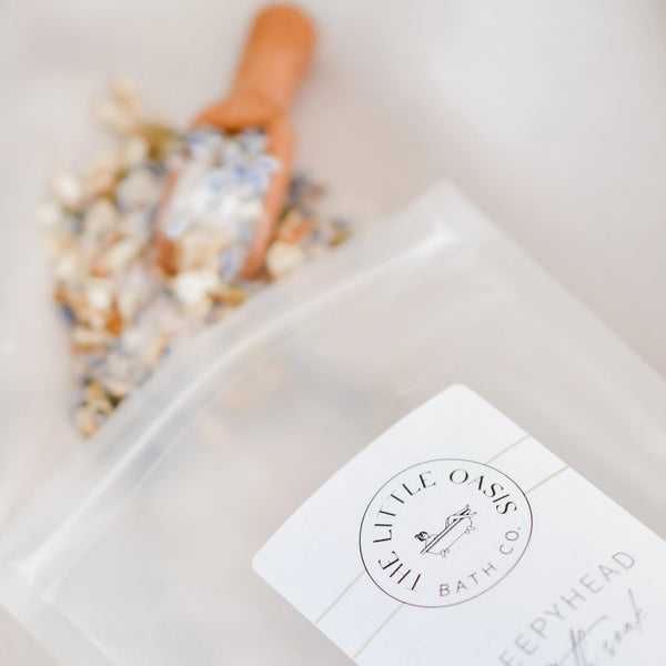 Bath soak packaging with 'Little Oasis Bath Co' logo on a blurred background