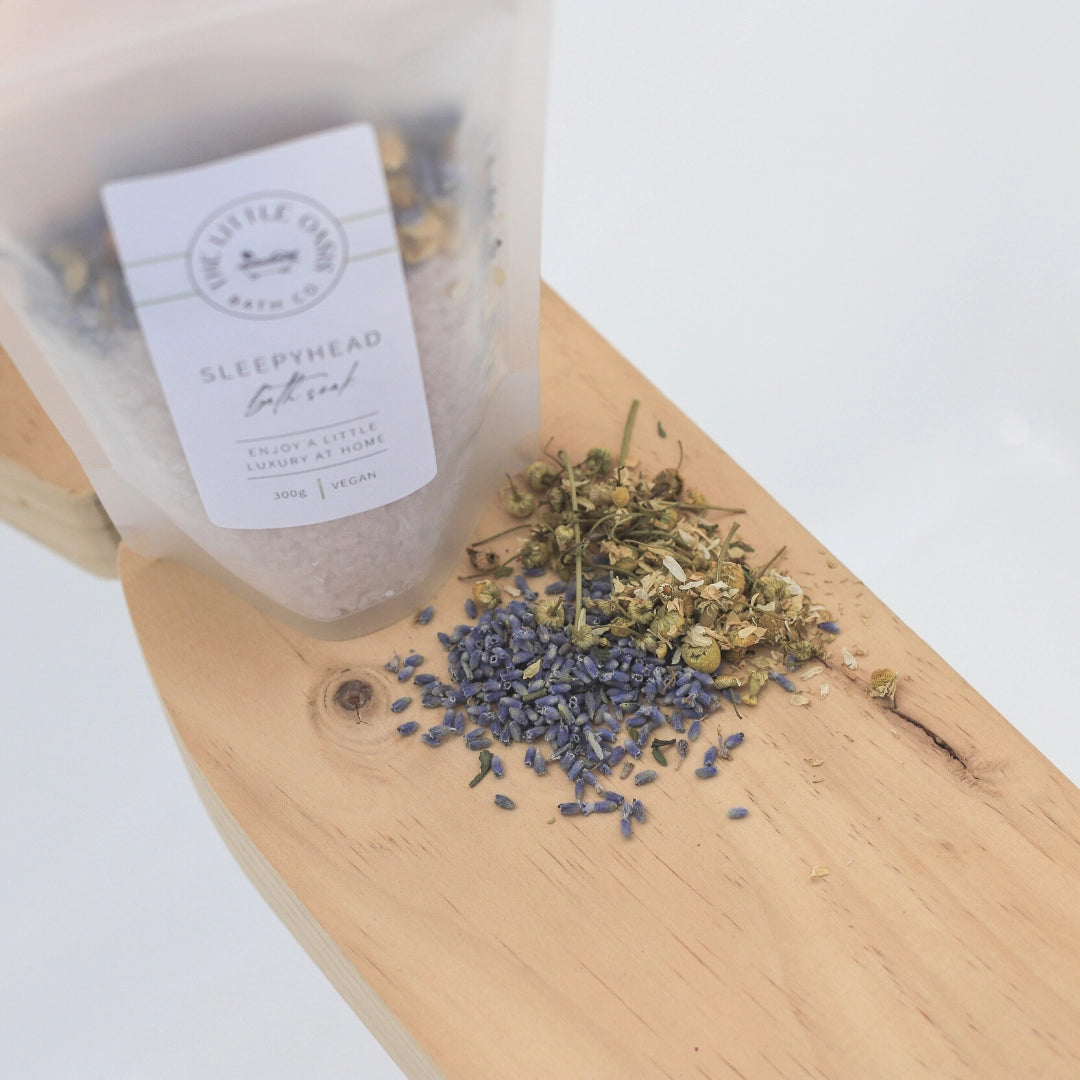 Bath salt packaging labeled 'Sleepyhead' with lavender buds on a wooden board.