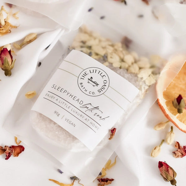 Bar of soap with a label on a white surface with dried flowers and leaves.