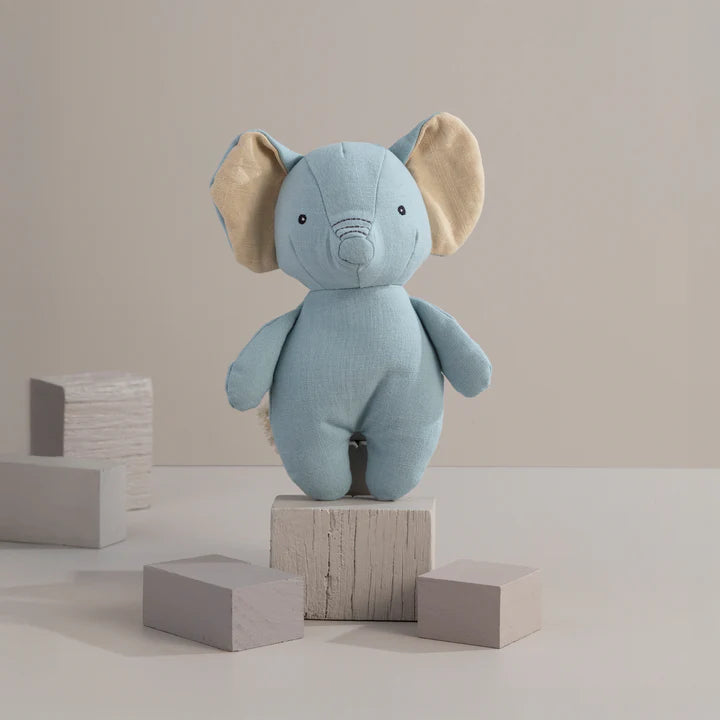Blue elephant plush toy on wooden blocks against a beige background