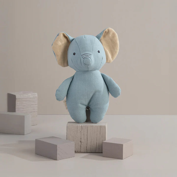 Blue elephant plush toy on wooden blocks against a beige background