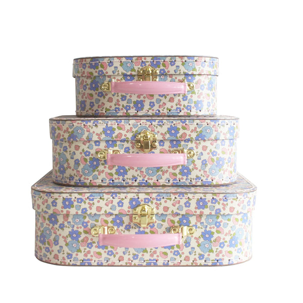 Set of three floral-patterned suitcases with pink handles on a white background