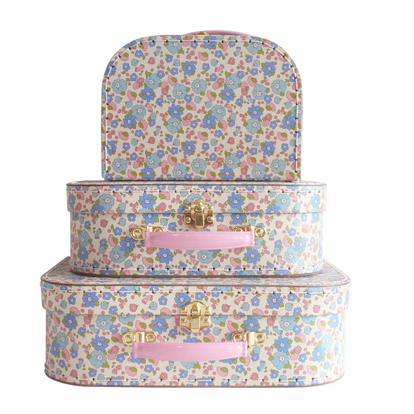 Set of three floral-patterned suitcases with pink handles on a white background
