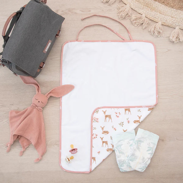 Baby care items including a pink bunny toy, diaper, and changing mat on a wooden surface.