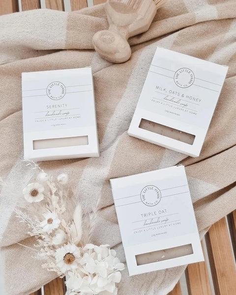 Three white boxes with branding on a beige fabric background