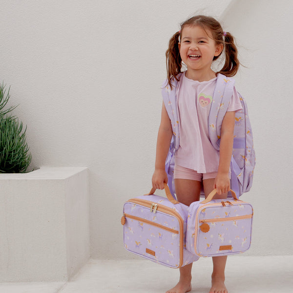 Child holding two matching purple bags with gold accents against a white background