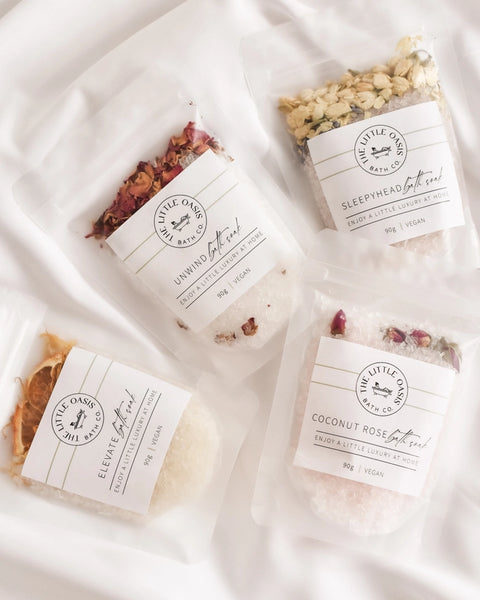Four packages of bath salts with labels on a white fabric background