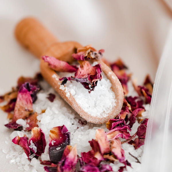 Wooden scoop with dried flowers and salt on a white background