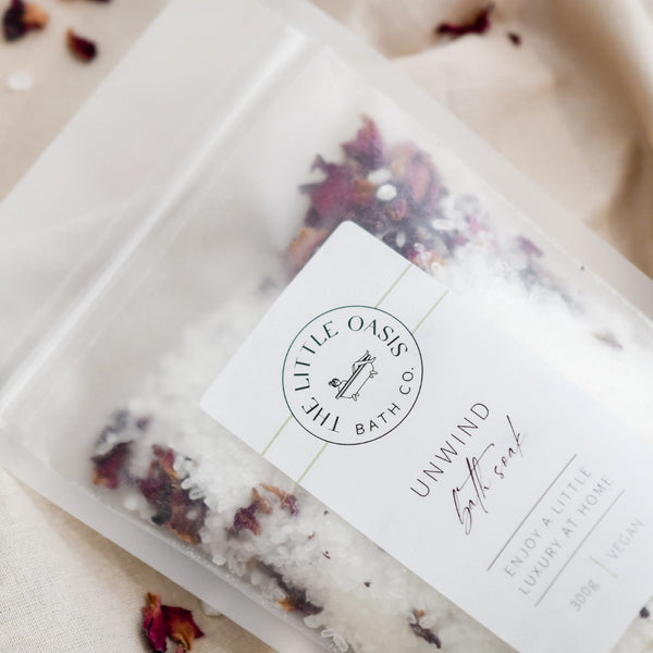 Bath salt package with dried flowers and 'Little Oasis' label on a neutral background