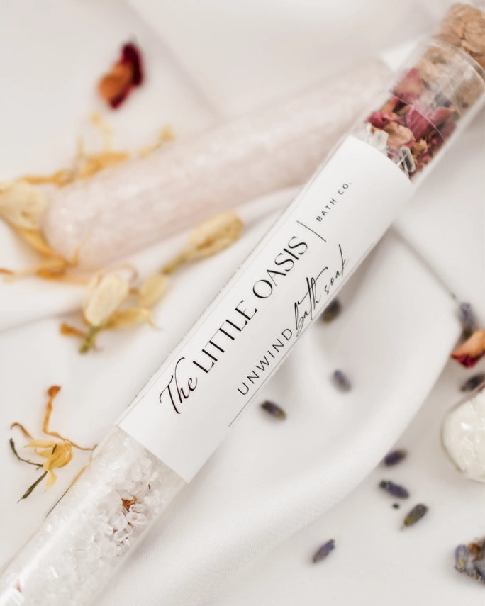 Bath soak packaging with 'The Little Oasis' branding on a decorative background with flowers and seashells.