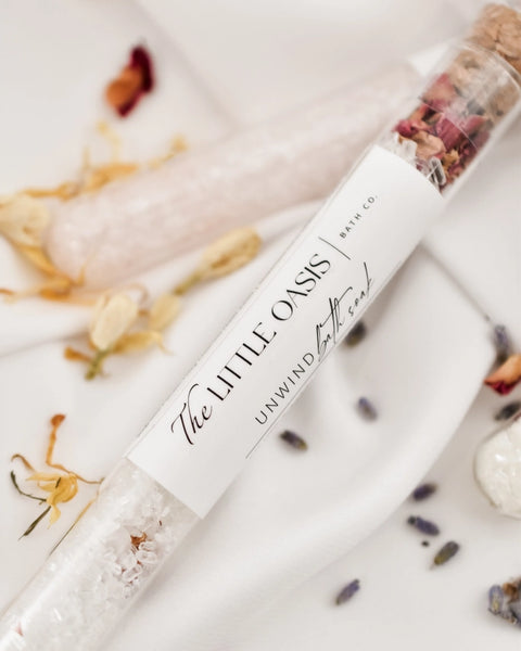 Bath soak packaging with 'The Little Oasis' branding on a decorative background with flowers and seashells.