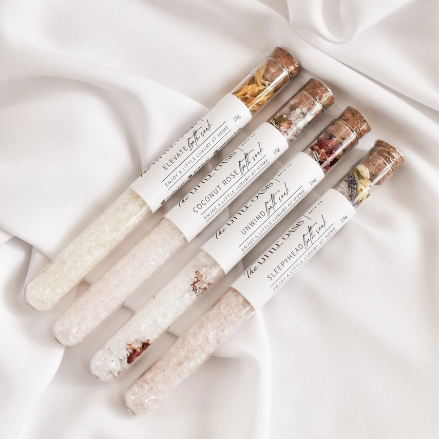 Set of four small labeled containers with decorative elements on a white fabric background