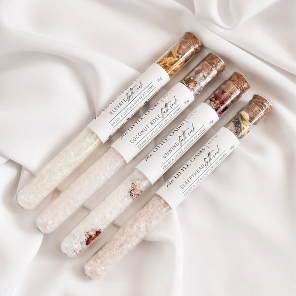 Set of four small labeled containers with decorative elements on a white fabric background