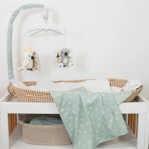 Baby crib with green blanket, toys, and white wall