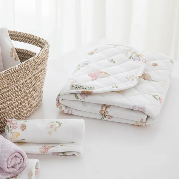 Floral-patterned baby blankets stacked on a white surface with a woven basket.