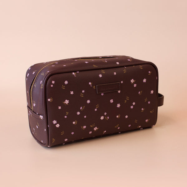 Brown toiletry bag with floral pattern on a beige background
