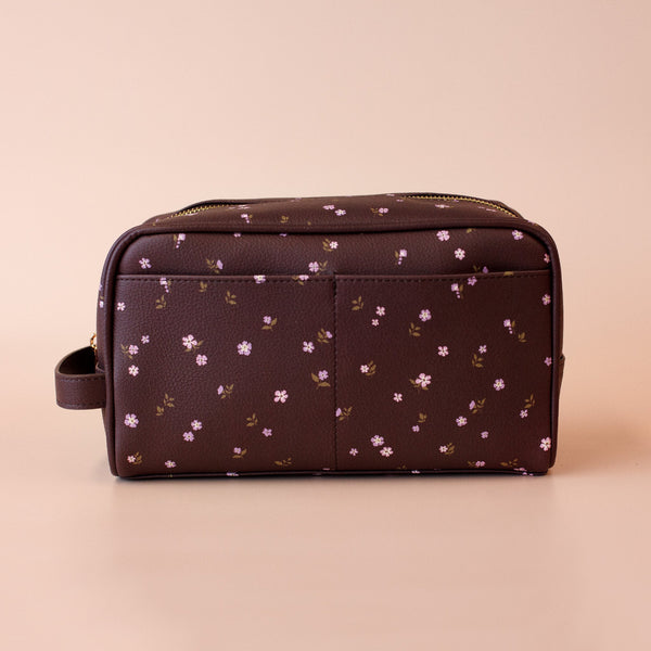 Brown toiletry bag with floral pattern on a beige background