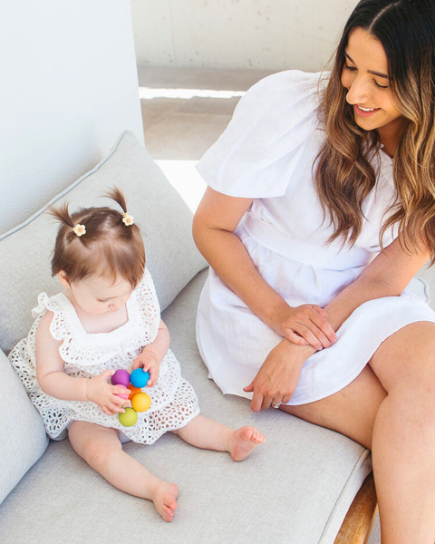 Woman and child sitting on a couch with colorful toys