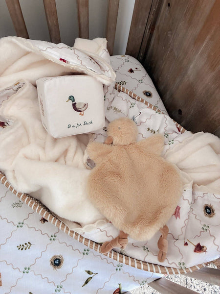 Baby crib with plush turtle toy and decorative pillow